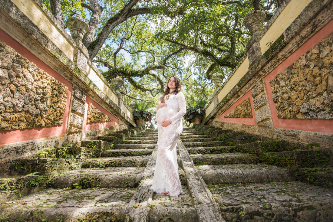 pregnancy picture mom holding belly in middle of stairs at Vizcaya museum and garden miami